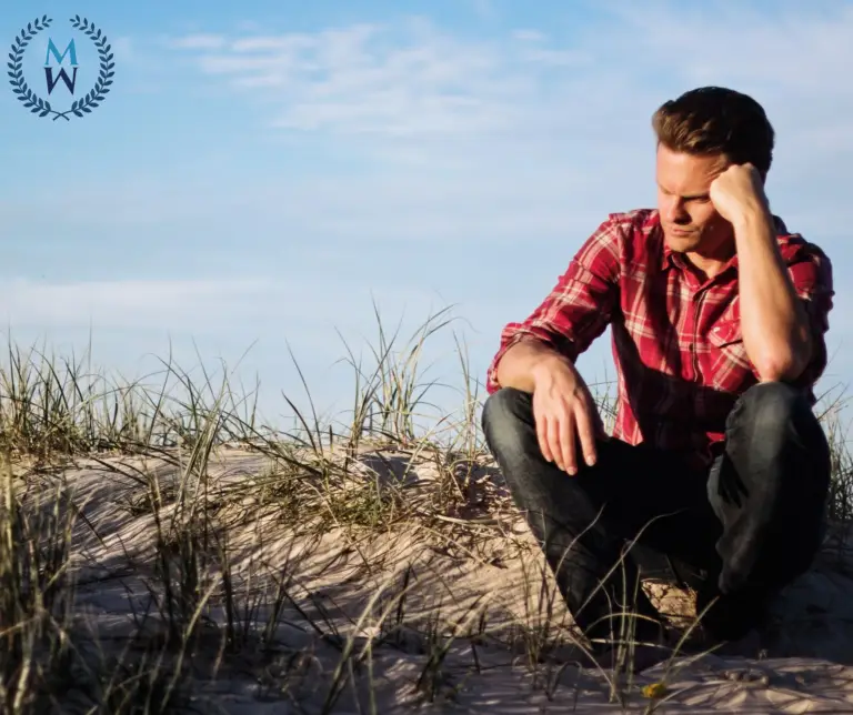 man sitting on sandy hill