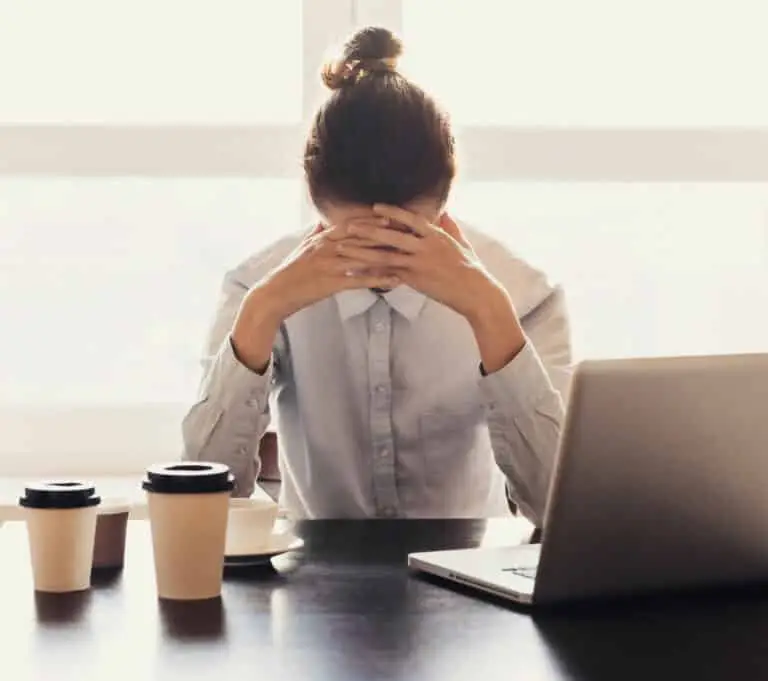 A woman with her head in her hands thinking about the recurring stress from trauma she has experenced