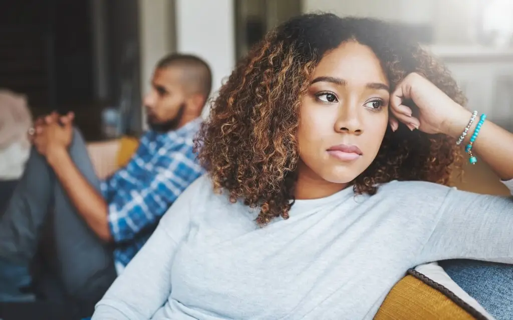 A couple sitting on a couch but facing away from each other.