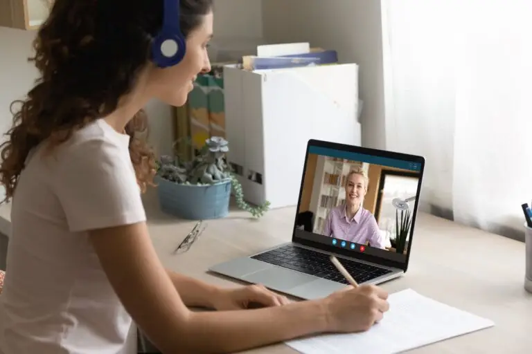 young woman with headphones on, taking notes while her online therapist talks to her about how her ADHD affects her sleep, and how to make it better.