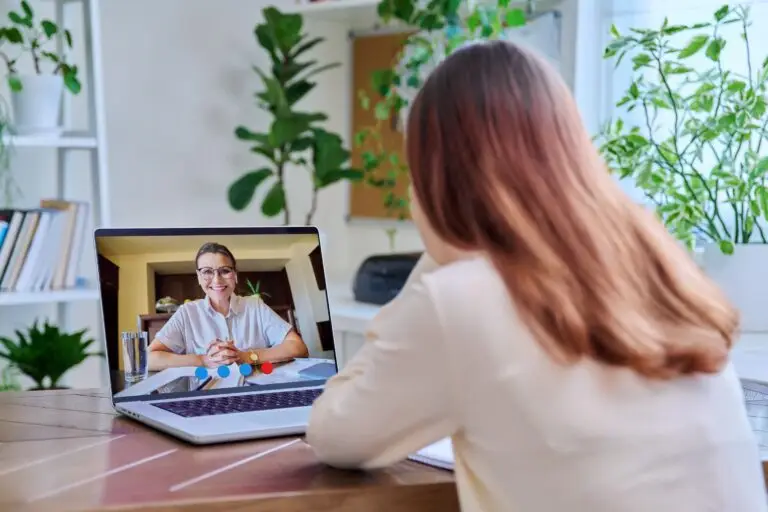 young woman using her computer to have an online therapy session with her therapist.