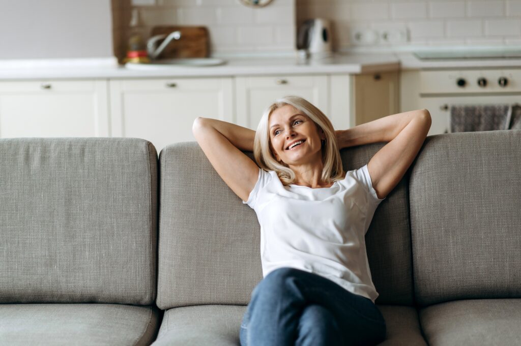 middle-aged woman relaxing on her couch, smiling peacefully after she healed herself after her divorce