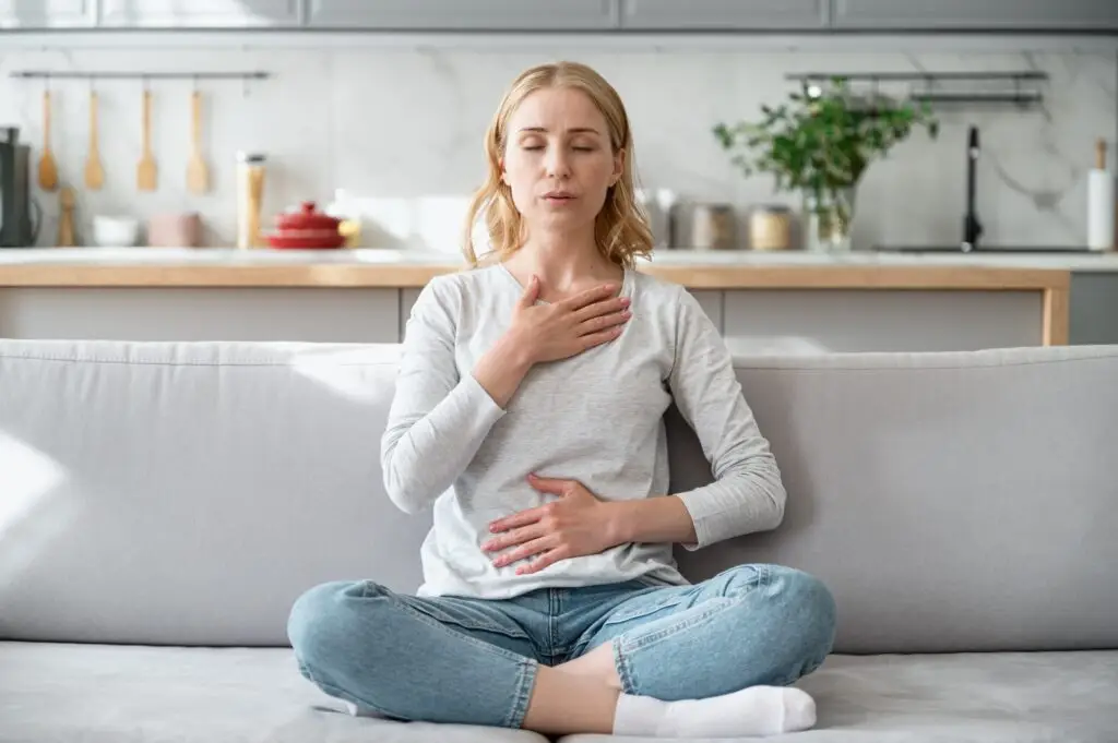 A young blonde woman using grounding techniques like calming breathing exercises after experiencing anxiety