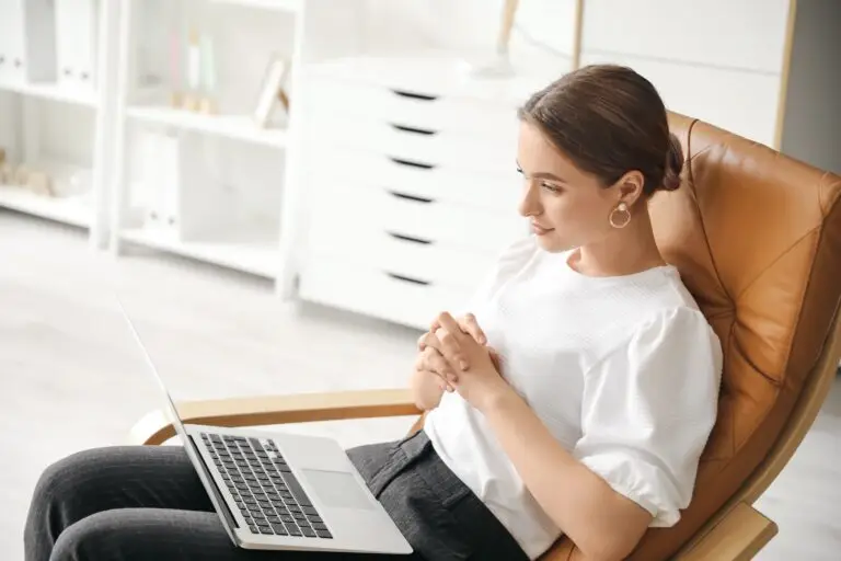 young professional woman sitting in her chair, happily talking to her mental health counselor to reduce stress and improve her mental health through online therapy