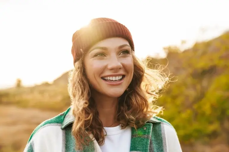 Young woman on a nature walk smiling in the sun because she learned how to reframe her thoughts.