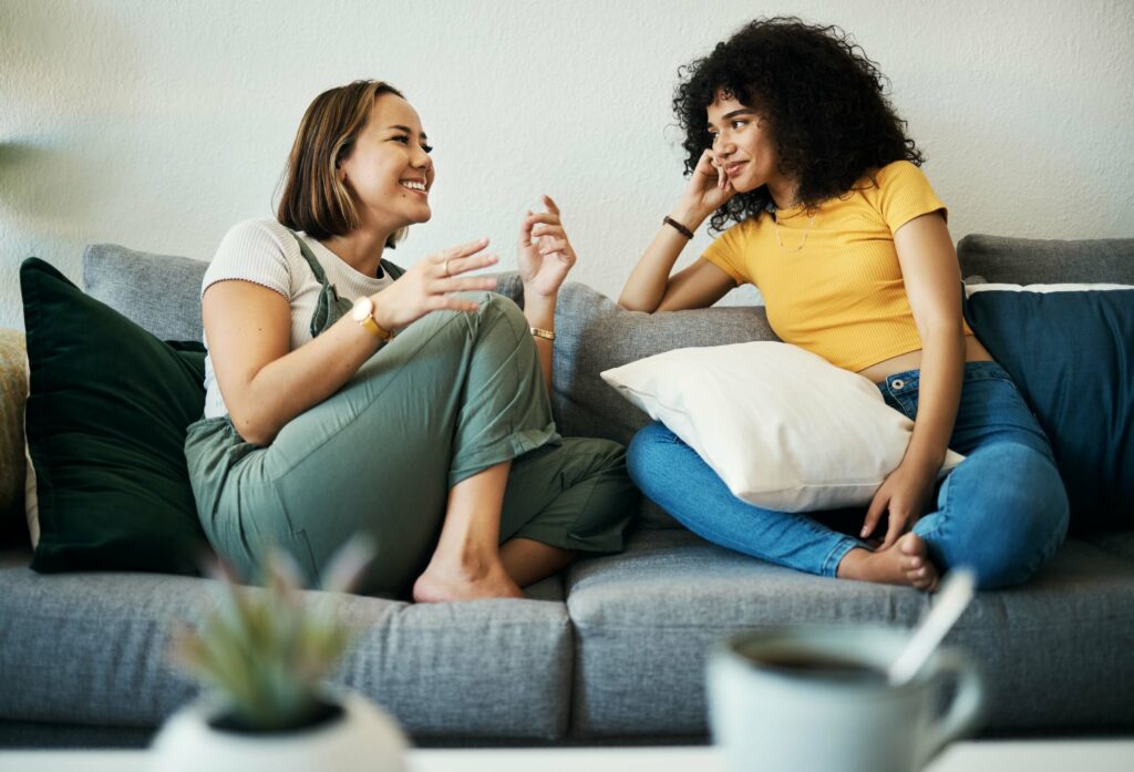 Two best friends are sitting cross-legged on a couch, talking intently about things important to each other. This type of connection is possible with high emotional intelligence.