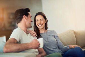 young man and woman couple sitting closely on the couch as they use their emotional literacy to communicate about what is important.