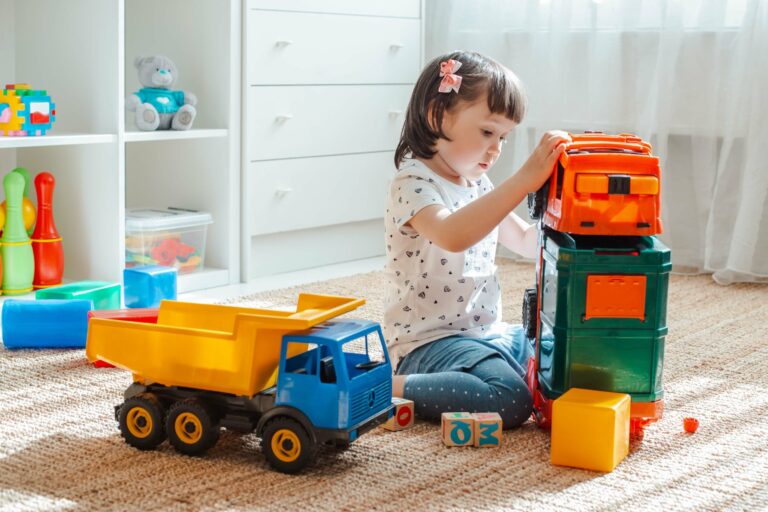 A little girl playing with her colorful toys on the floor.