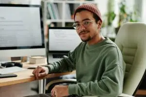 a young man sitting at his desk looking back to the camera.