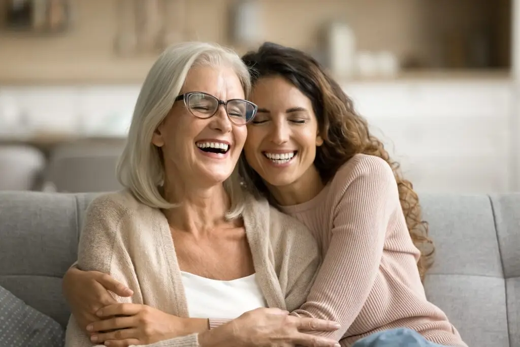 A mother and daughter embracing in a happy side hug on the couch.