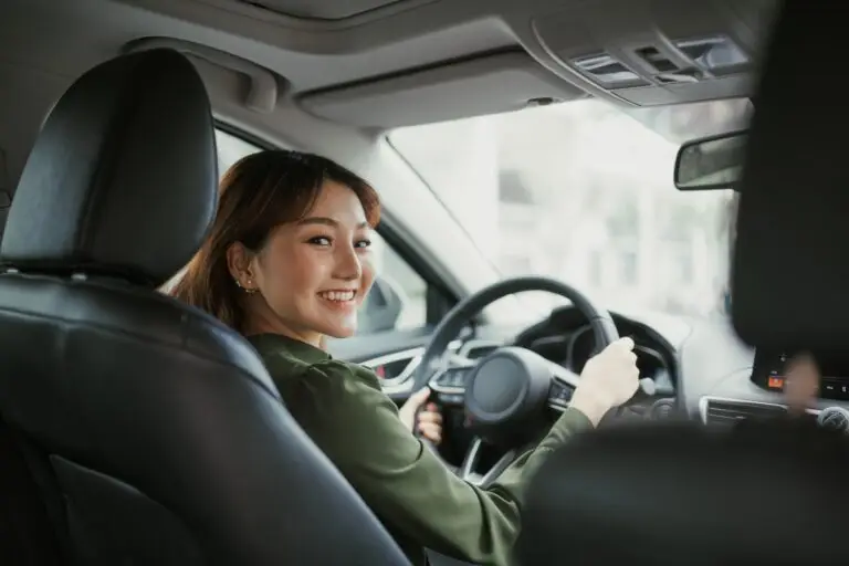 Young woman smiling wide because she finally left her house to drive a car after overcoming her agoraphobia symptoms.