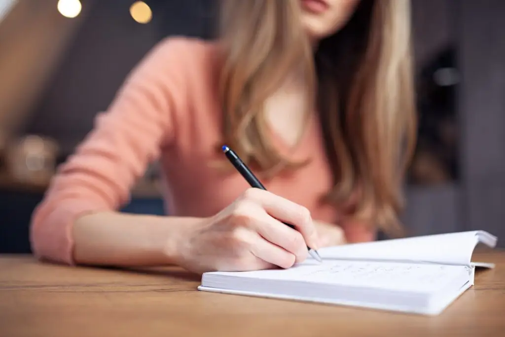 Young blonde woman writing in her journal the times her partner displays gaslighting behavior.