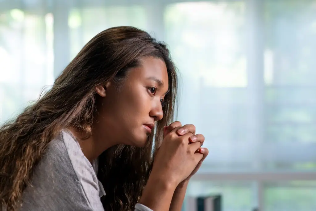 Young lady looking out her window feeling stressed and afraid to leave her house.