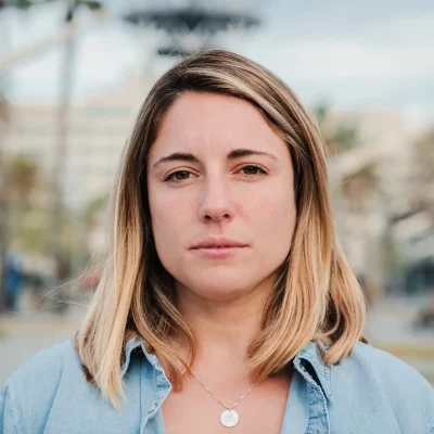 A young blonde woman staring into the camera as she works through her difficult feelings.