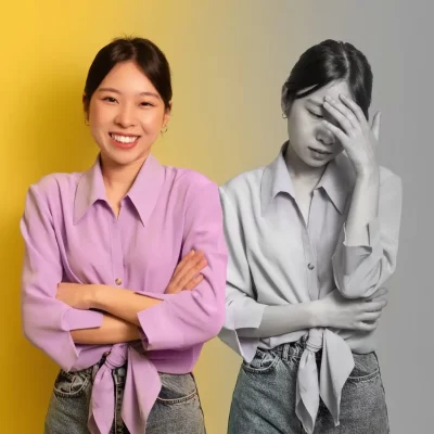 Eustress vs distress: young asian woman in a bright pink blouse smiling happily with her arms crossed. a mirror image of herself in black and white next to her, fingertips on her forehead, in a state of stress