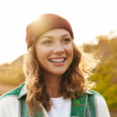 Young woman on a nature walk smiling in the sun because she learned to reframe her thoughts and find happiness again.