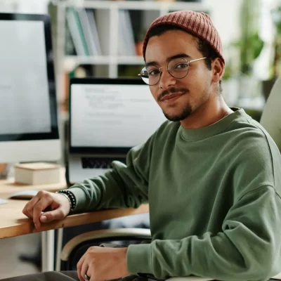 a young man sitting at his desk looking back to the camera.